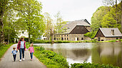 Familie spaziert am Fluss entlang, umgeben von den historischen Gebäuden des Sauerlands.