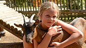 Mädchen streichelt eine Ziege im Kleintierbereich des Familienhotels Family Club Harz. Im Rahmen der Kinderbetreuung werden die lieben Tiere regelmäßig besucht.