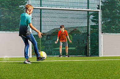Zwei jugendliche Jungs spielen auf dem Fußballplatz des Elldus Resorts Fußball.