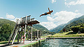 Mann springt vom Turm in ein Outdoor Wasserbecken auf dem Außengelände des Familienhotels Sailer.