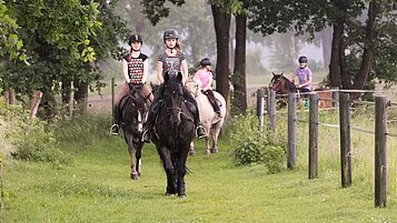 Kinder bei Ausritt mit Ponys und Pferden inmitten herrlicher Natur
