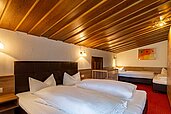 Ein Familienzimmer mit Doppelbett und zwei Einzelbetten im Familienhotel Lärchenhof in Tirol