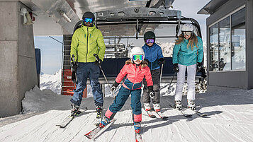 Winter im Salzburger Land: Familie fährt aus dem Skilift raus. Und los geht der Skispaß!