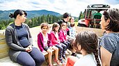 Kinder sitzen auf dem Hänger hinter dem Trecker und fahren zum Hotel im Familienhotel Der Ponyhof Steiermark.