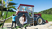 Familie spielt zusammen auf einem outdoor Traktor-Spielplatz im Familienhotel Schreinerhof.