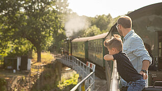 Vater und Sohn sehen sich die historische Bahn im Erzgebirge an.