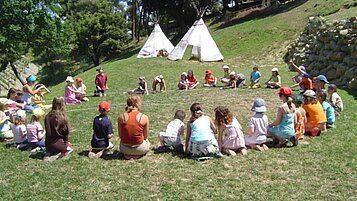 Kinder sitzen im Kreis mit Indianerzelten im Familienhotel Castellare di Tonda in der Toskana 