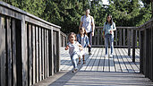 Wandern in Oberösterreich: Familie wandert auf dem Baumkronenweg. Kind rennt lachend voraus.