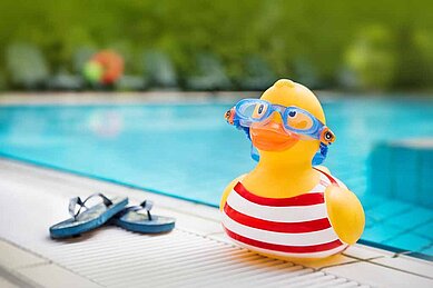 Bade-Ente und Badeschuhe liegen am Beckenrand des Außenpools im Familienhotel Sonnenhügel.