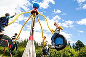 Mehrere Kinder spielen auf dem Outdoor Spielplatz im Familienhotel Lärchenhof in Tirol