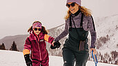 Mutter und Tochter stapfen im Schnee durch die verschneite Landschaft in Südtirol.