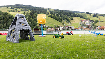 Große Spielwiese mit Kletterstein, Tracktoren und Fußballtor im Wellness- & Familienhotel Egger in Saalbach Hinterglemm.