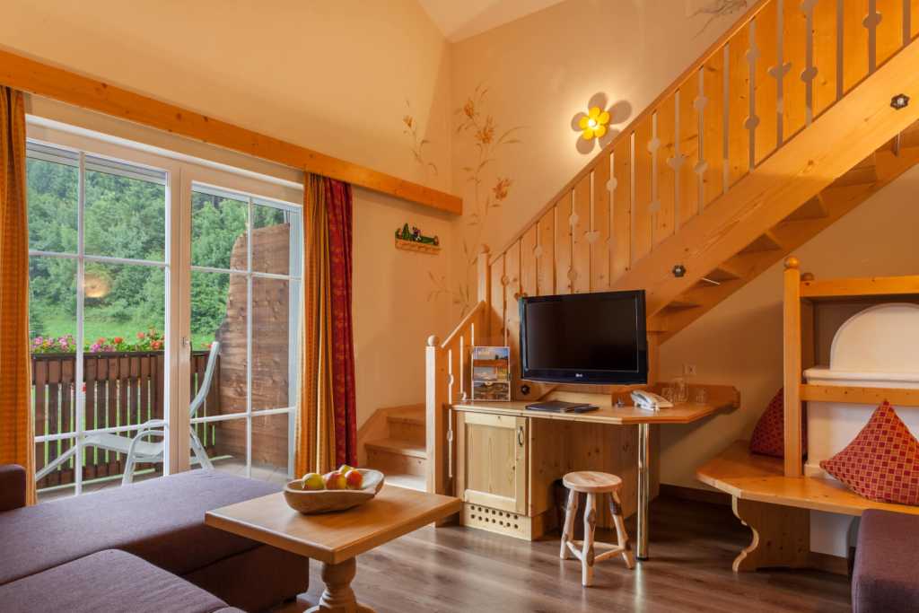 Wohnbereich mit einem Balkon in der Familiensuite im Familienhotel Alphotel Tyrol Wellness & Family Resort in Südtirol.
