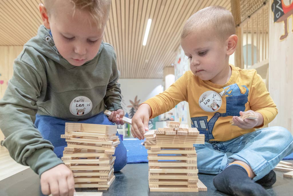 Kinder sitzen in der Kinderbetreuung am Basteltisch und basteln ein Nest mit ihrer Betreuerin im Familienhotel Gorfion in Lichtenstein.