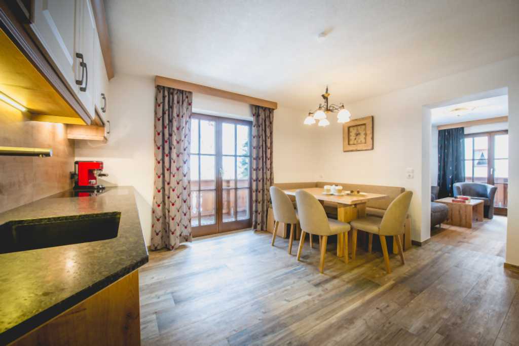 Geräumiges Familienzimmer mit eigenem Wohnzimmer und Küchenzeile im Familienhotel Alpenhotel Kindl in Tirol.