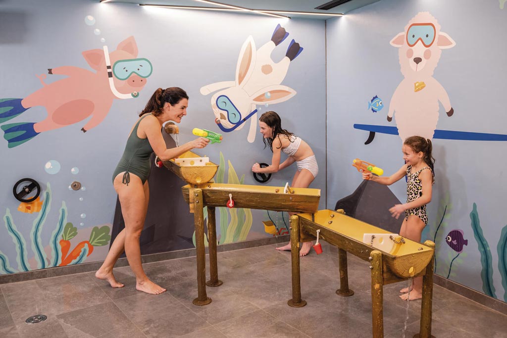 Familie spielt auf dem Indoor Wasserspielplatz im Hallenbad des Familienhotels Alpenhotel Kindl in Tirol.