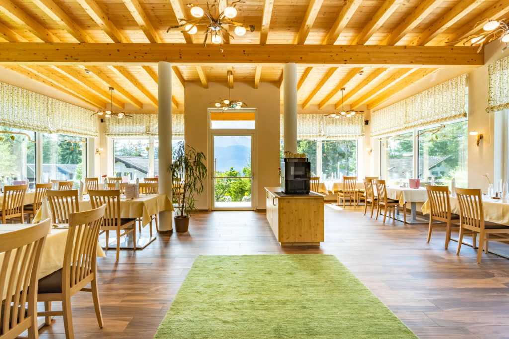 Das große, lichtdurchflutete Restaurant mit Tischen und Stühlen aus Holz im Familienhotel Lärchenhof in Tirol