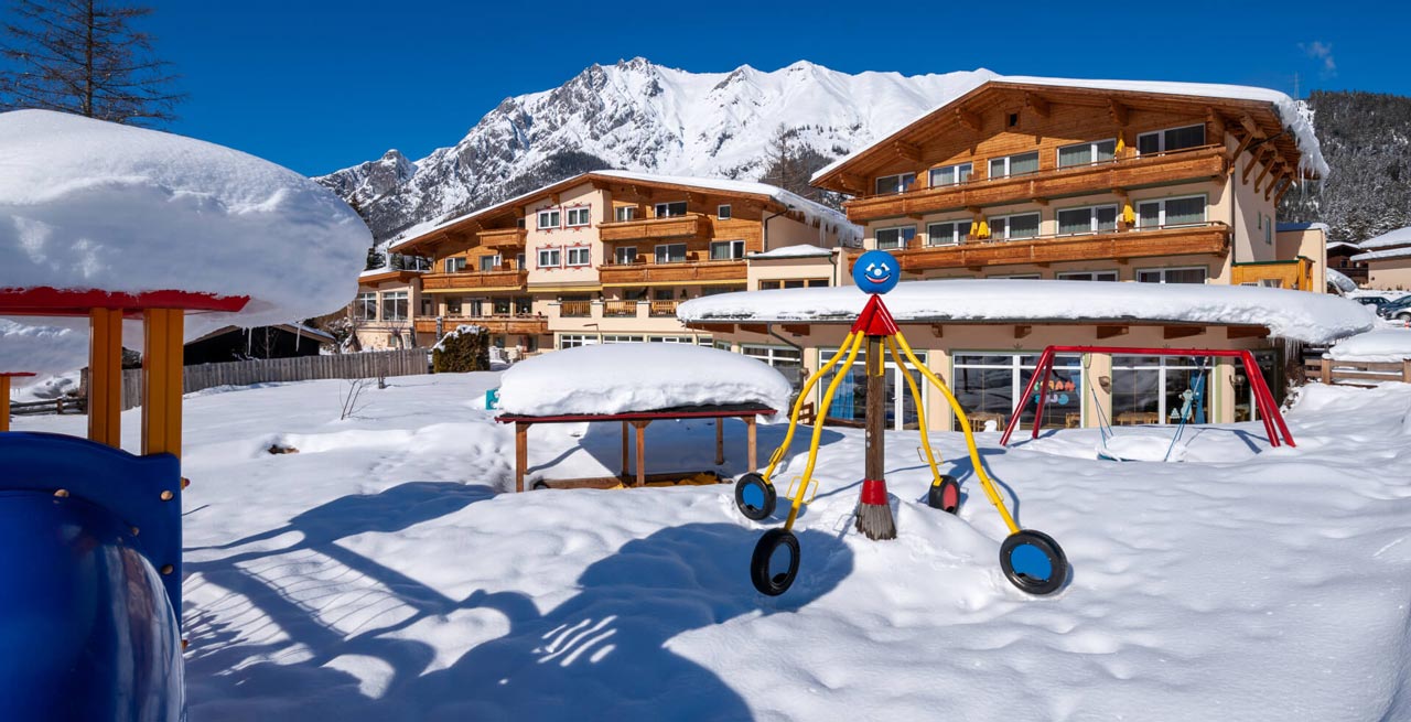 Das Familienhotel Lärchenhof in der Winterlandschaft von der Sonne bestrahlt. 