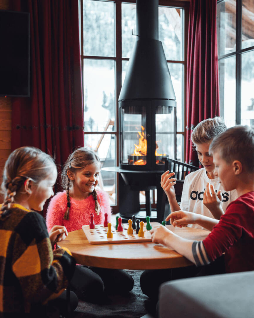 Kinder spielen Gesellschaftsspiele im Mons Silva Private Luxury Chalet in Südtirol.