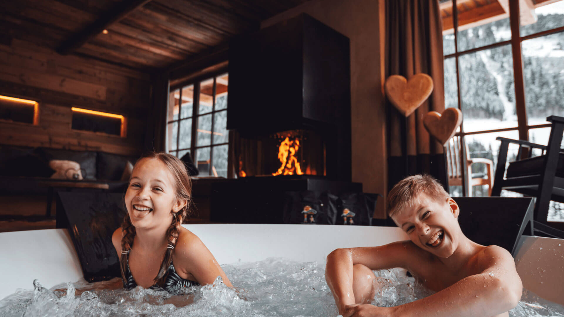 Kinder sitzen im privaten Chalet-Whirlpool im Familienurlaub im Mons Silva Private Luxury Chalet.