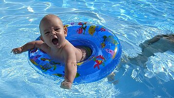 Lachendes Baby im Schwimmreifen im Kinderpool.