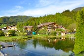 Außenansicht des Familienhotels Landgut Furtherwirt im Sommer mit einem Naturbadeteich direkt vor der Tür.