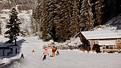 Eine Familien fährt auf Ski den Ski- und Rodelhang neben dem Familienhotel Habacklause hinunter