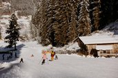 Eine Familien fährt auf Ski den Ski- und Rodelhang neben dem Familienhotel Habacklause hinunter
