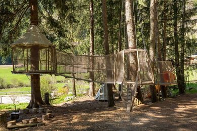Netzpfad mit Hängebrücke und Baumplattformen im Abenteuerspielplatz des Familienhotels Huber in Südtirol