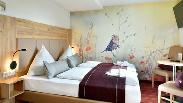 Doppelbett mit bunter Tapete im Familienhotel Rhön Feeling.