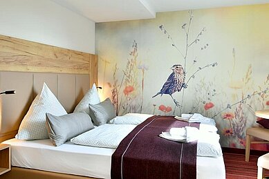 Doppelbett mit bunter Tapete im Familienhotel Rhön Feeling.