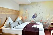 Doppelbett mit bunter Tapete im Familienhotel Rhön Feeling.