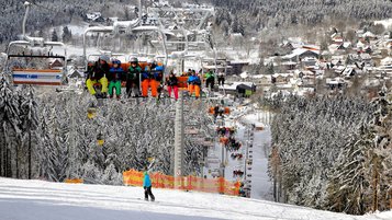Kinder sitzen im Skilift und fahren oben auf den Berg