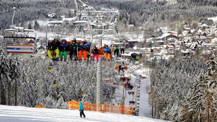 Kinder sitzen im Skilift und fahren oben auf den Berg