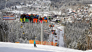 Kinder sitzen im Skilift und fahren oben auf den Berg