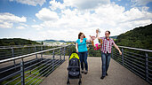 Junge Familie beim Spaziergang mit Kinderwagen.