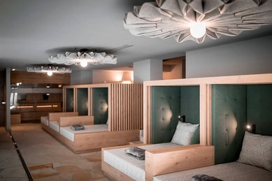 Moderner Ruhebereich im Familienhotel Alpenhof Dolomit Family mit gemütlichen Liegen und stimmungsvoller Beleuchtung für erholsame Wellnessmomente.