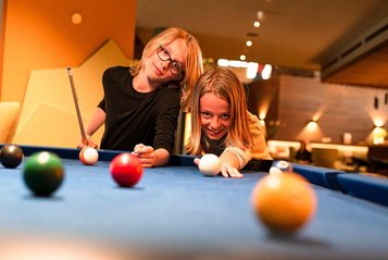 Teenager beim Billard spielen im Familienurlaub