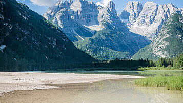 Ausblick auf eine Bergkette und einem See mit Ufer und strahlenden Himmel. Ein toller Sommer in Südtirol für jeden Teenager.
