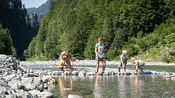 Familie planscht im klaren Fluss in Vorarlberg.