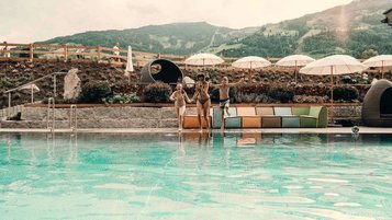 Kinder springen voller Freude in den Außenpool des Familienhotel Mia Alpina in Tirol.
