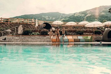 Kinder springen voller Freude in den Außenpool des Familienhotel Mia Alpina in Tirol.