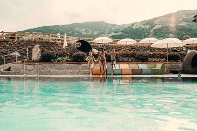 Kinder springen voller Freude in den Außenpool des Familienhotel Mia Alpina in Tirol.
