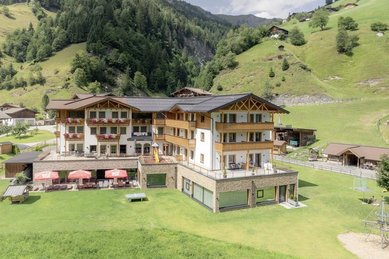 Das Familienhotel Oberkarteis im Salzburger Land ist aus der Vogelperspektive mit der umliegenden Wiese und Berglandschaft zu sehen.