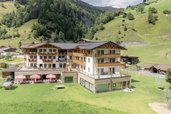 Das Familienhotel Oberkarteis im Salzburger Land ist aus der Vogelperspektive mit der umliegenden Wiese und Berglandschaft zu sehen.