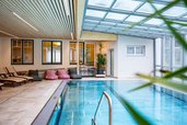 Heller Indoor-Pool mit Relaxliegen und Sitzsäcken im Familienhotel Bruckwirt für entspannte Stunden am Wasser.