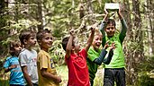 Kinder des Familienhotels Engel Gourmet & Spa sind auf einem Ausflug mit dem Happy-Club im Wald in Südtirol.
