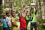 Kinder des Familienhotels Engel Gourmet & Spa sind auf einem Ausflug mit dem Happy-Club im Wald in Südtirol.