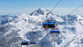Familie bei einer Fahrt mit dem Sessellift über die verschneiten Berge rund um das Familienhotel Ramsi in Kärnten