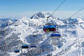 Familie bei einer Fahrt mit dem Sessellift über die verschneiten Berge rund um das Familienhotel Ramsi in Kärnten
